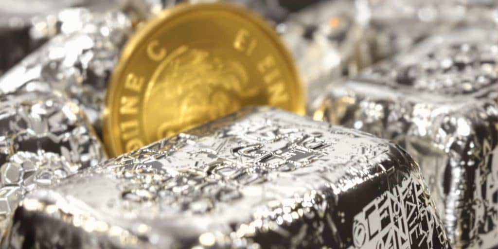 Lingots d'argent brillant avec une pièce d'or en arrière-plan.