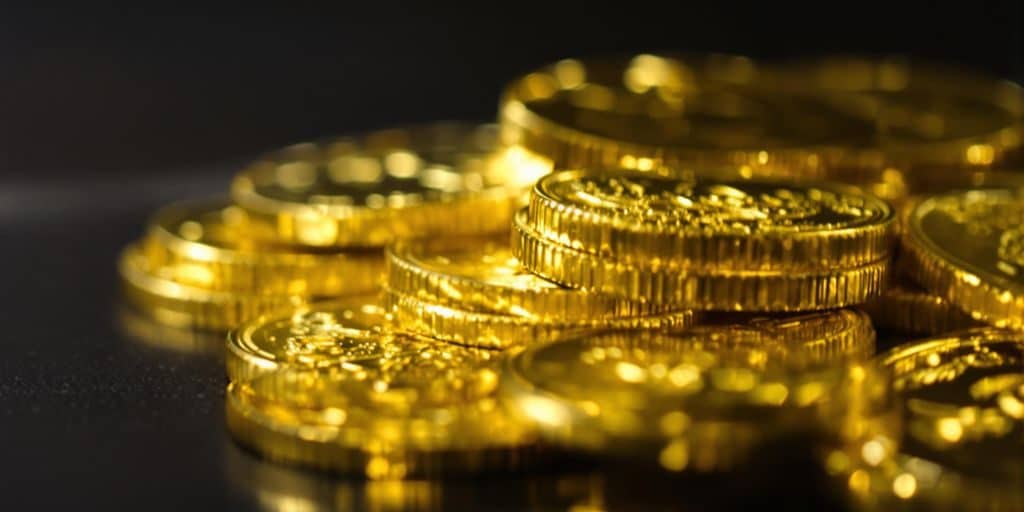 Plusieurs pièces d'or brillantes empilées sur un fond sombre.
