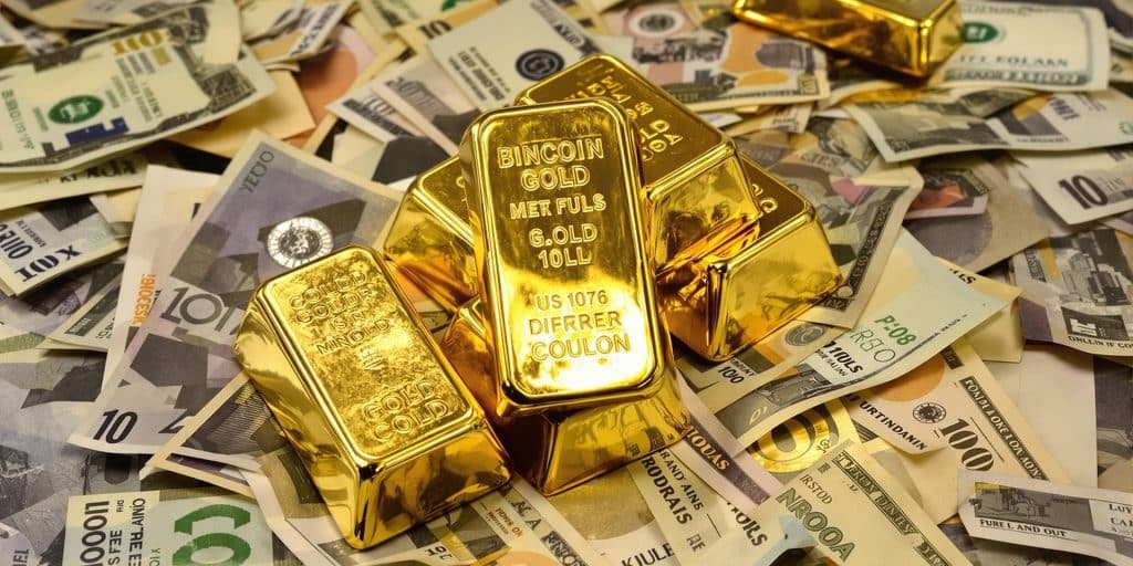 Lingots d'or sur fond de billets de banque.