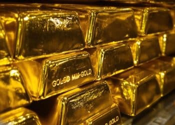 Lingots d'or brillants empilés dans une chambre forte sécurisée.