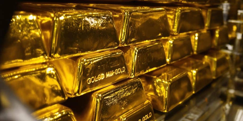 Lingots d'or brillants empilés dans une chambre forte sécurisée.