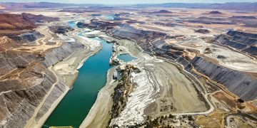 Une rivière traverse un paysage minier, reliée à des infrastructures.