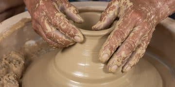 Mains travaillant l'argile pour créer une poterie ornée.