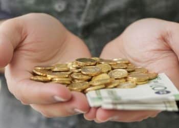 Une main tenant des pièces d'or et des billets.