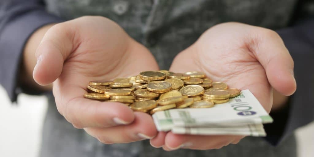 Une main tenant des pièces d'or et des billets.