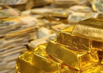 Pile d'or sur fond de billets allemands anciens.