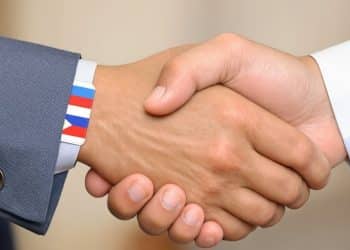 Mains serrant des drapeaux nationaux dans un accord diplomatique.