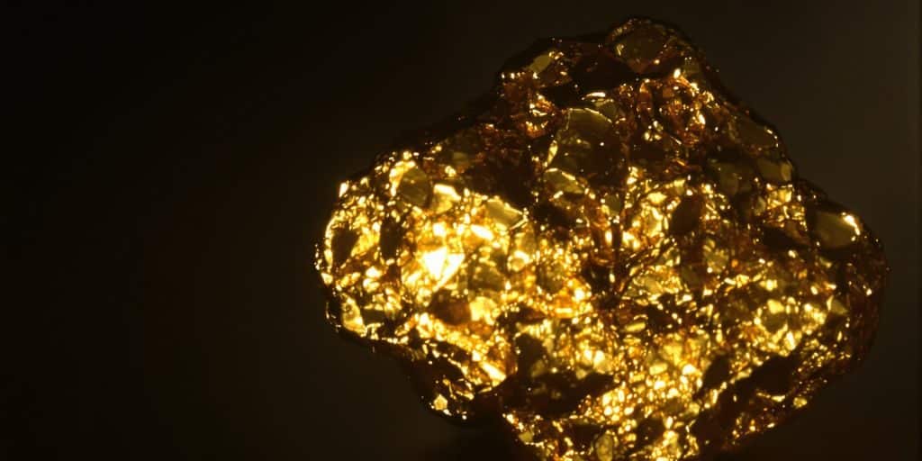 Petite pépite d'or brillante sur fond sombre.