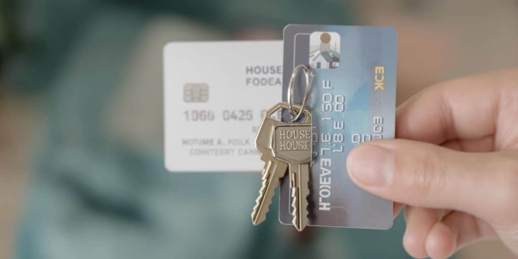 Une main tenant une clé de maison et une carte de crédit.