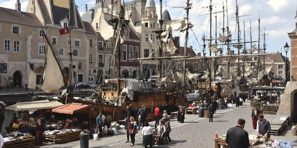 An old merchant ship sailing into a medieval port.