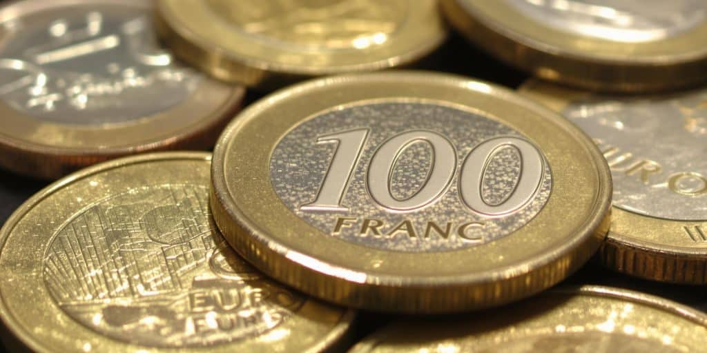 Pièces de 100 francs argent et euros sur fond neutre.