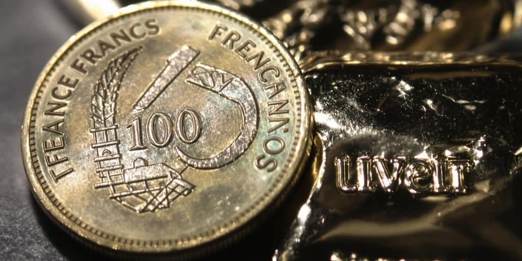 Une pièce de 100 francs en argent à côté d'un lingot d'argent.