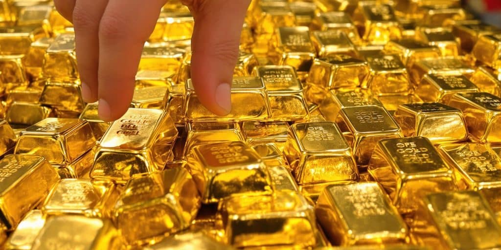 Une pile d'or brillant à côté d'une main hésitante.
