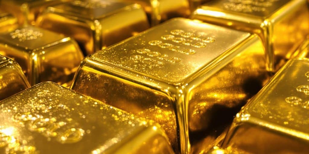 Lingots d'or brillant sous une lumière dorée.