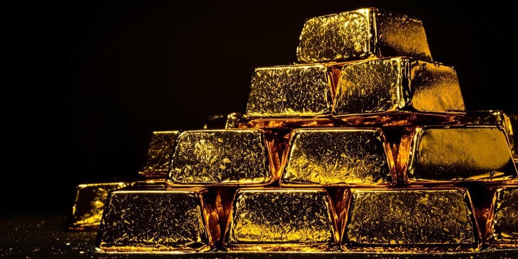 Lingots d'or brillants empilés sur une surface sombre.