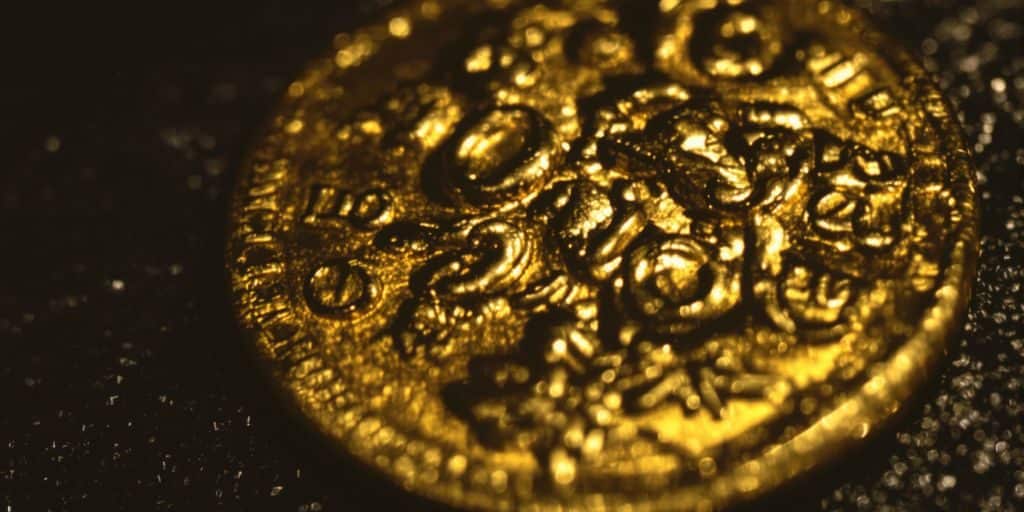 Pièce d'or ancienne brillant sous un éclairage dramatique.