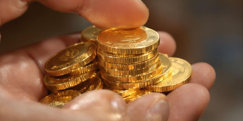 Main d'une personne tenant une pile de pièces d'or.