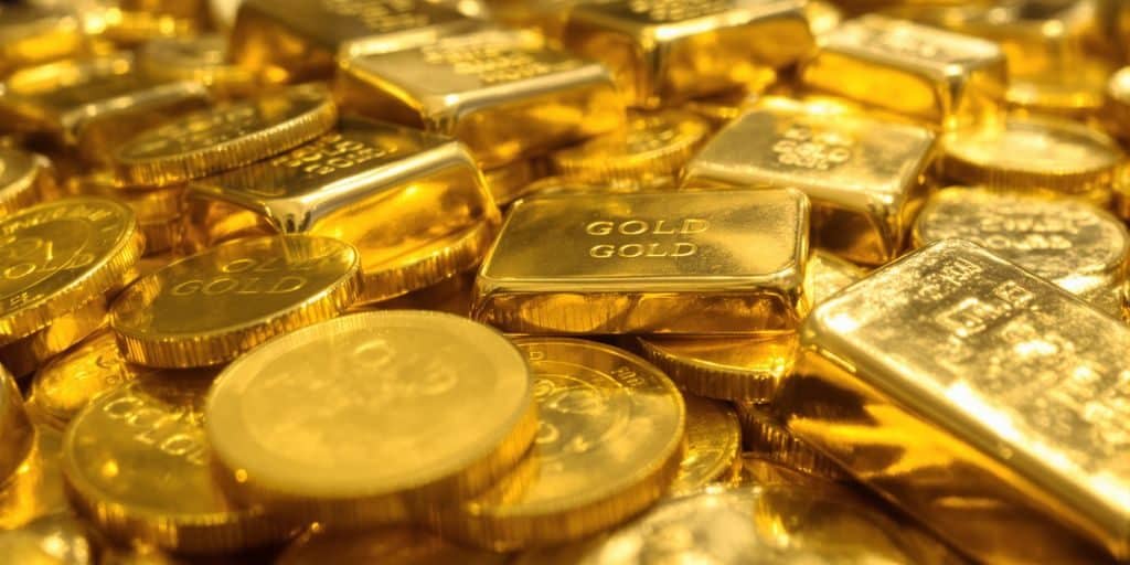 Lingots d'or brillants et pièces d'or empilées dans une main.