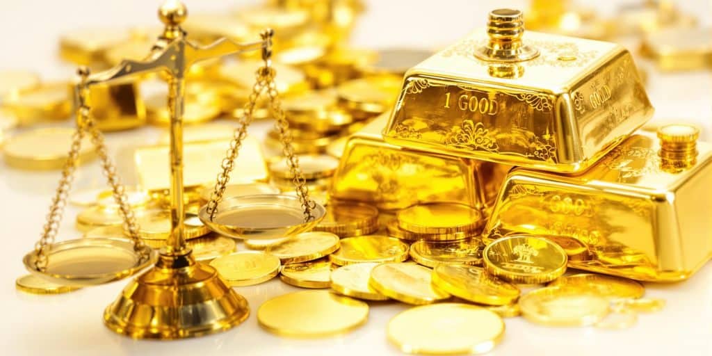 Lingots d'or brillants, pièces d'or, et une balance.