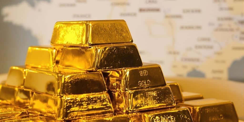 Lingots d'or empilés avec des cartes de France floues en arrière-plan.