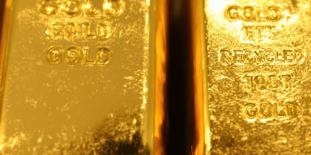 Lingots d'or brillants sous une lumière dorée.