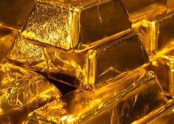 Lingots d'or brillants sous un éclairage dramatique.