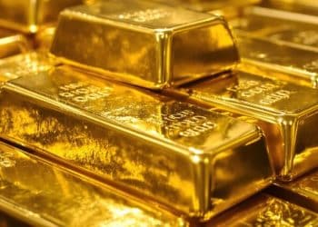 Lingots d'or brillants sous une lumière tamisée.
