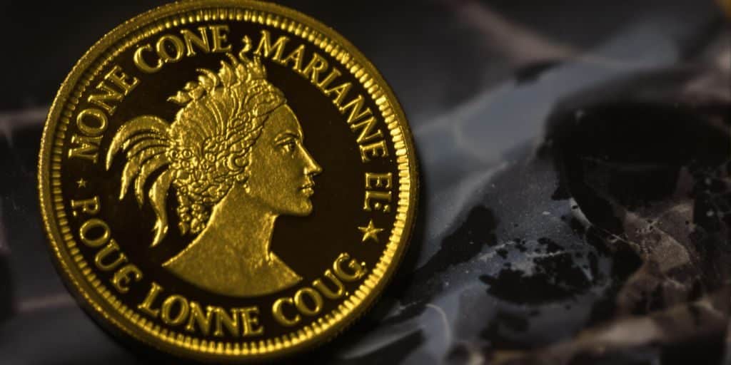 Une pièce Marianne Coq dorée sur un fond sombre.
