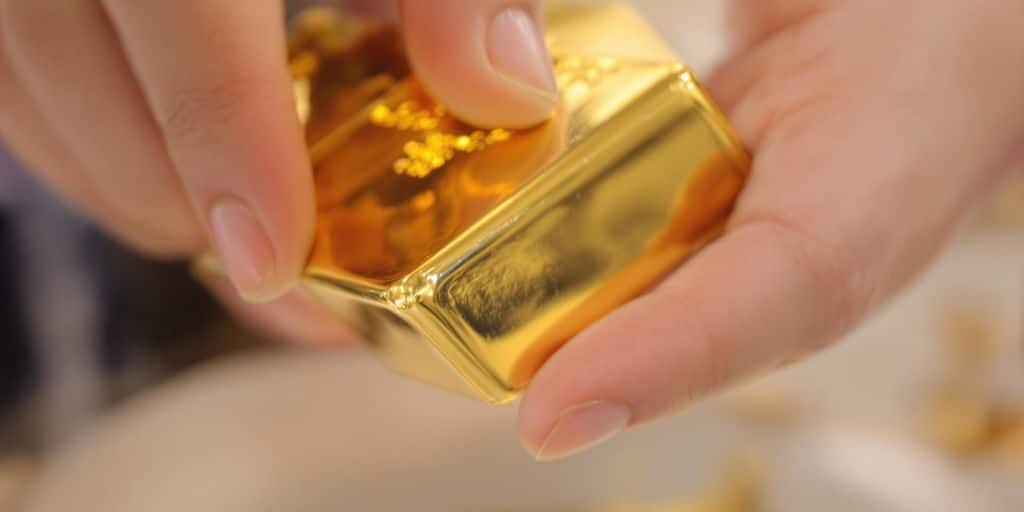 Une main tenant une barre d'or brillant.