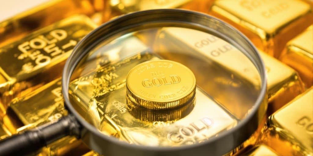 Lingots d'or brillant, une loupe examinant une petite pièce d'or.