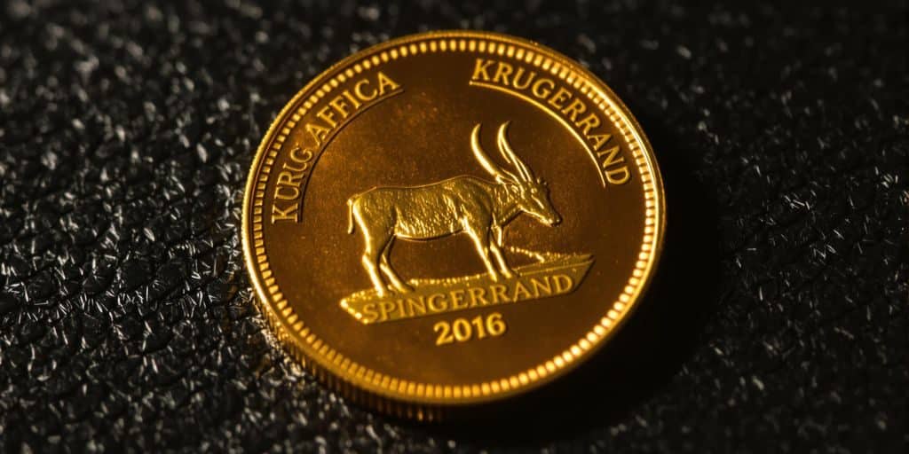 Un lingot d'or Krugerrand posé sur un fond neutre.